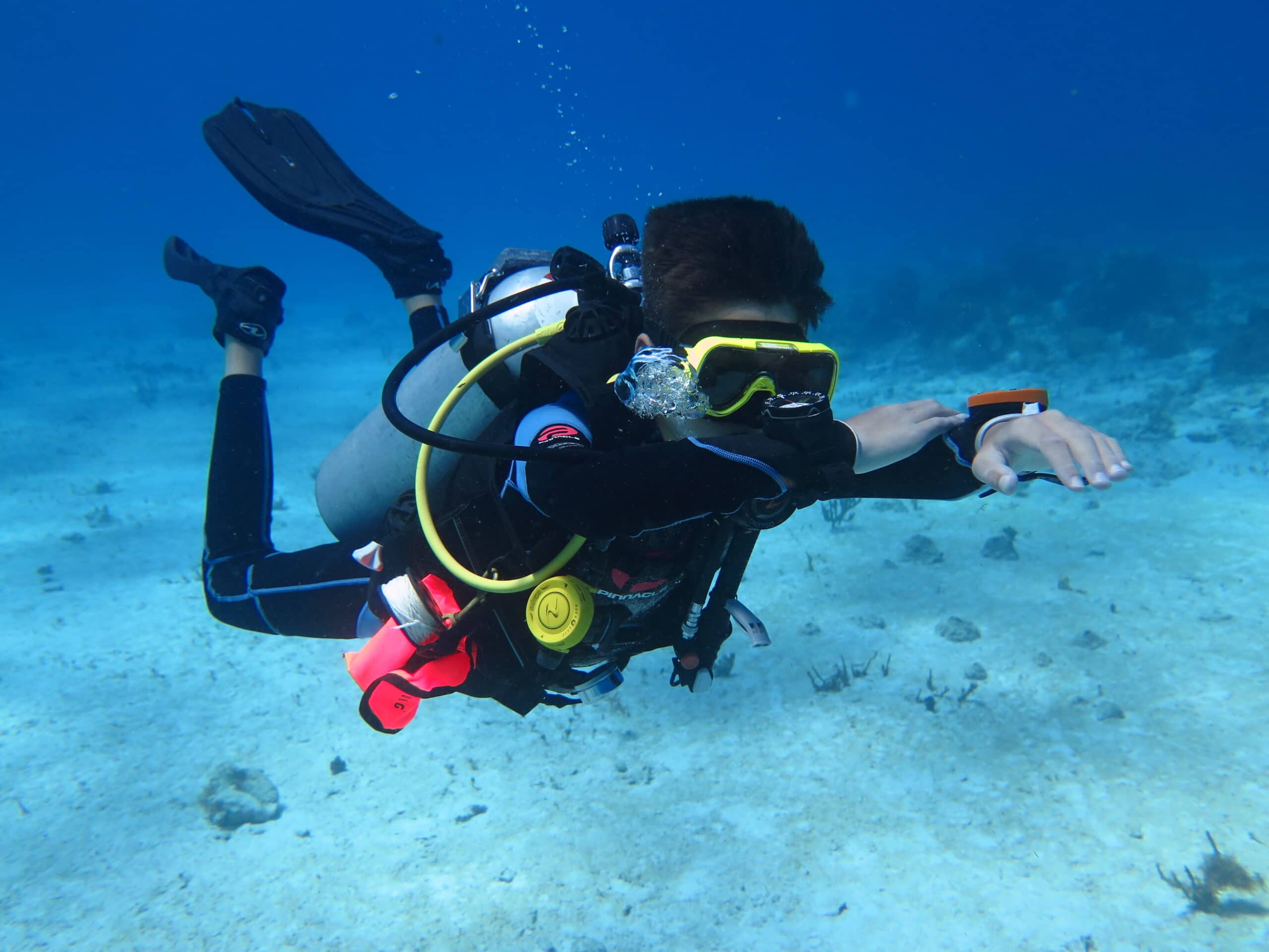 A young Advanced Open Water student performs compass exercises underwater.