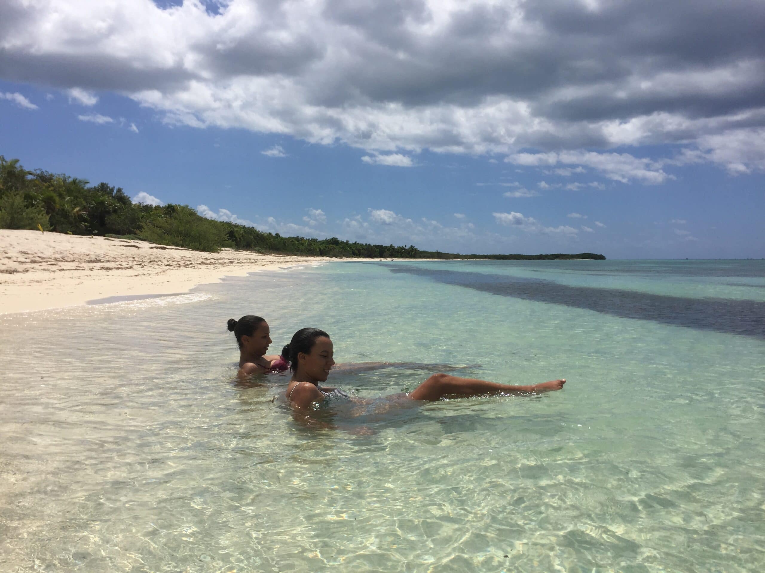 Two female private snorkelers relax in very shallow water for a break during their private snorkeling day.