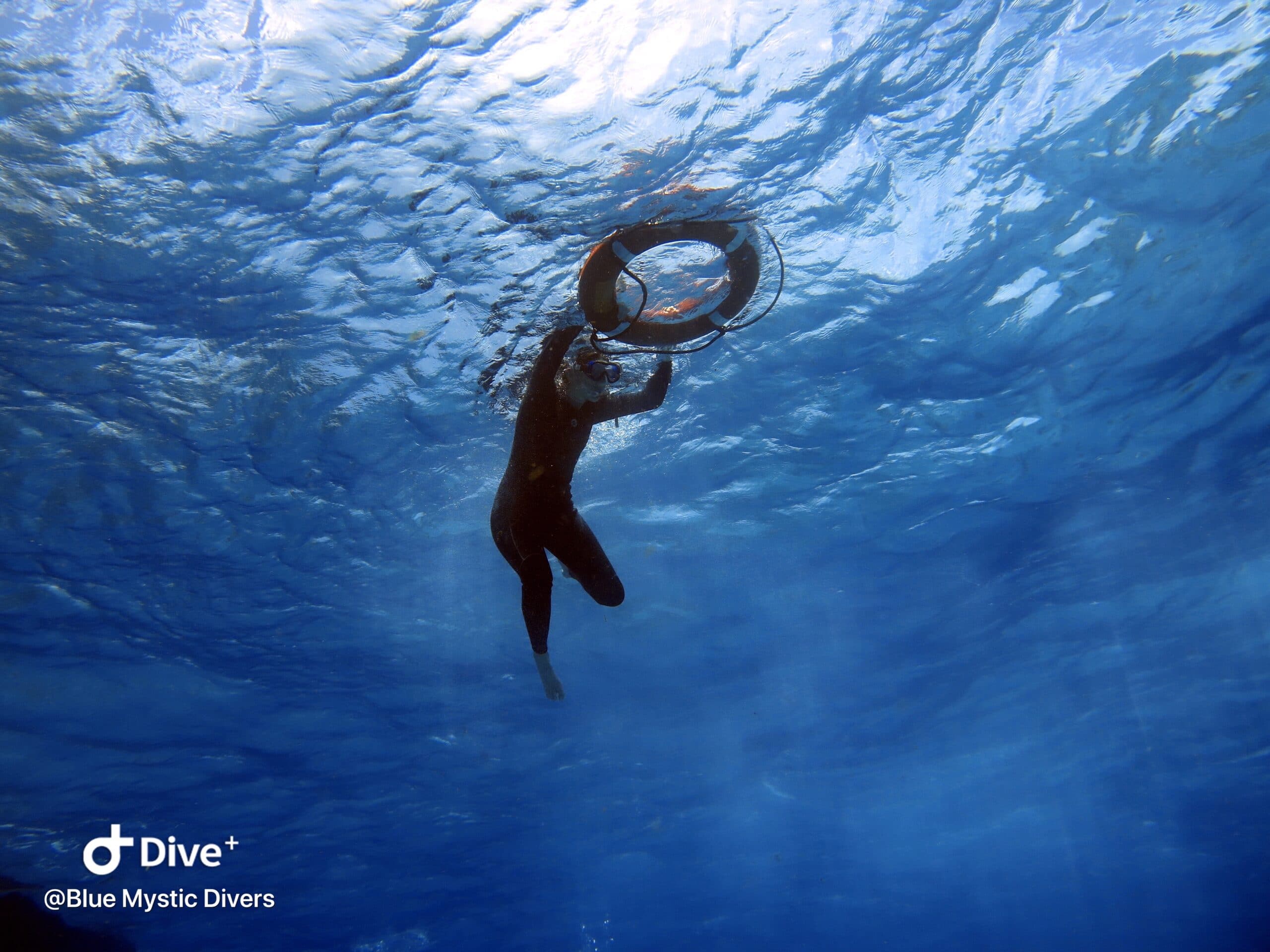 Underwater photo of a snorkeler at the surface of the sea, light shining above.